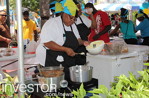 A vendor makes conch fritters for the crowds
